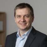 Портрет уверенного российского бизнесмена с дружелюбным взглядом на размытом нейтральном фоне студии